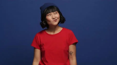 A smiling asian woman is plotting something standing isolated over blue wall Stock Footage 157763482