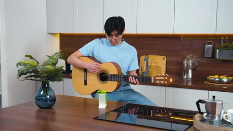 Smiling asian young man study play guitar by video call with teacher. Home kitch Stock Footage 162612412