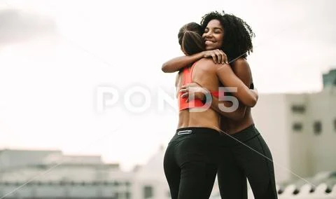 Smiling athlete giving a hug to her friend during workout Stock Photos