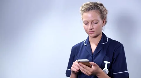 Smiling attractive good looking nurse using mobile phone against white backgr 스톡 동영상 59087307