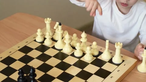 Smiling baby boy arranges white chess pieces on the board at home. Stock Footage 150480845