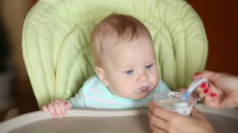 Smiling baby eating food on kitchen in his chair Stock Footage 56561653