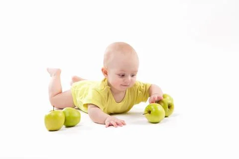 Smiling baby lying on the background to include apples Stock Photos