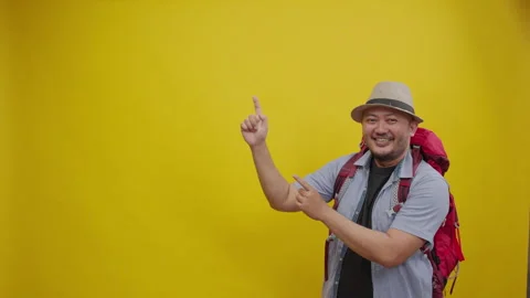 Smiling Backpacker Wearing a Hat and Red Backpack Pointing Up Toward Copy Space Stock Footage 336994791