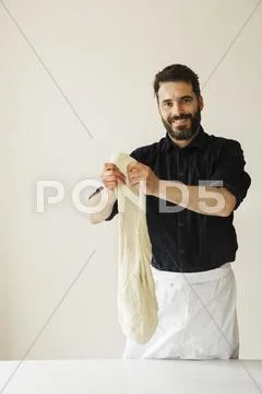 Smiling baker holding up a large portion of bread dough. Stock Photos