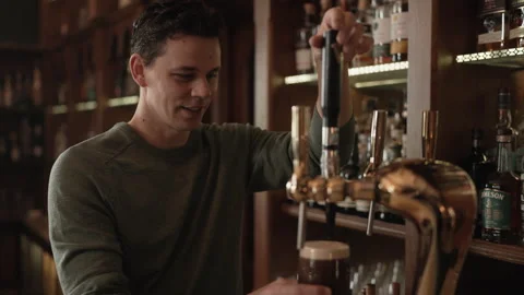Smiling bartender pulling a pint of dark Guinness beer at a bar. Stock Footage 242172164