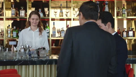 Smiling bartender serving drinks to customers at a modern bar Stock Footage 316364099