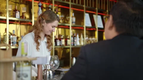 Smiling bartender serving drinks to customers at a modern bar Stock Footage 316364740
