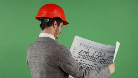 Smiling bearded engineer in hardhat examining blueprints with confidence Stock Footage 311923687