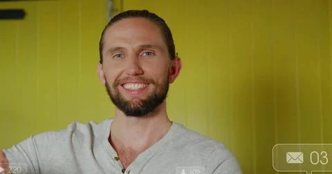 Smiling bearded man looking at camera in studio on yellow wall, showing digital Stockfoto's