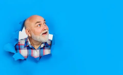 Smiling bearded man looking through paper hole. Handsome senior man in plai.. Stock Photos