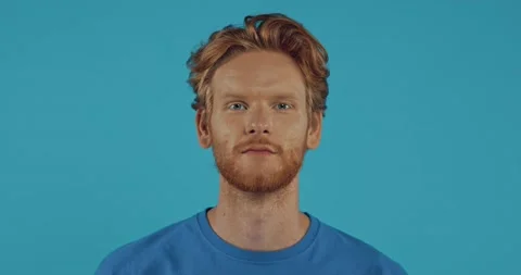 Smiling bearded redhead man looking around isolated on blue Stock Footage 136178344