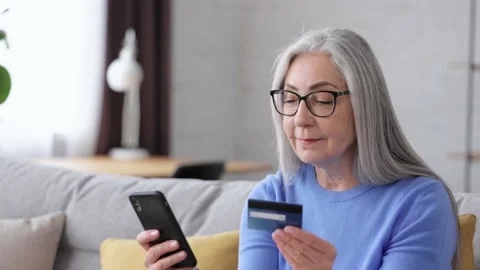 Smiling beautiful elderly gray-haired woman shopping online holding credit card Stock-Footage 213279215