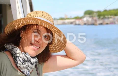 Smiling beautiful woman with straw hat while cruising in the sea Stock Photos