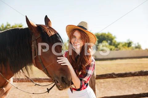 Smiling beautiful young woman cowgirl with her horse on farm Stock Photos