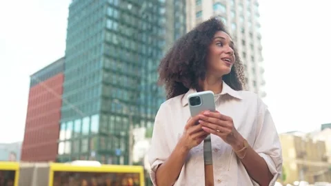 Smiling beautiful young woman using smartphone outdoors. Female with curly hair Stock Footage 311543304