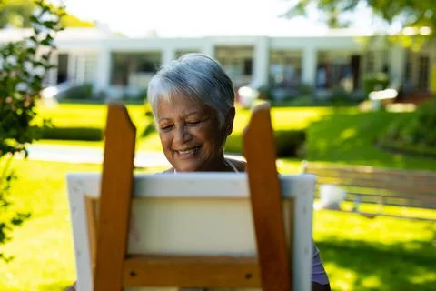 Smiling biracial senior woman with short gray hair painting on canvas against Stock Photos