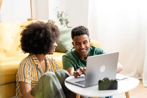 Smiling black couple using laptop at home Stock Photos