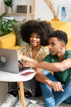 Smiling black couple using laptop at home Foto stock