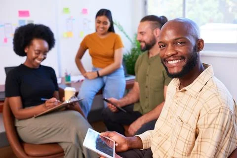 Smiling Black developer man with team having informal meeting, creative office Stock Photos