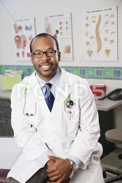 Smiling Black Doctor Sitting In Doctor's Office