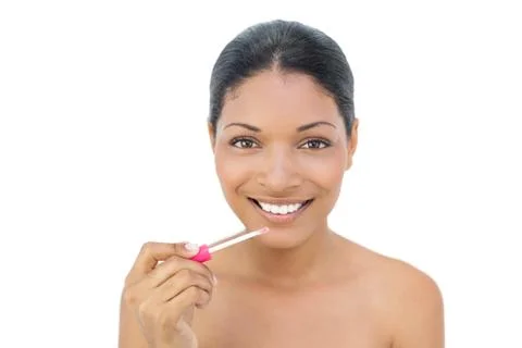 Smiling black haired model applying lip gloss Stock Photos