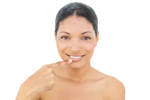 Smiling black haired model pointing at her bottom lip Stock Photos