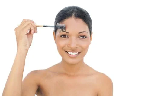 Smiling black haired model using eyebrow brush Stock Photos