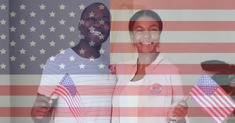 Smiling Black man and Asian woman holding US flags with VOTE badges at home, Stock Photos