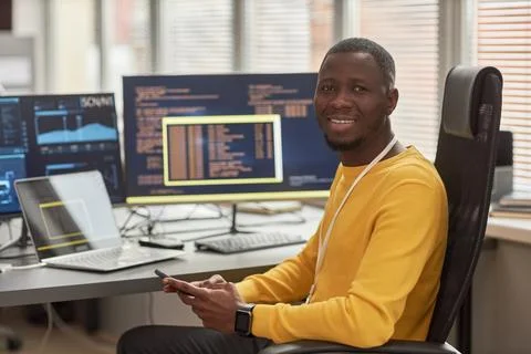 Smiling black man looking at camera at workplace in software development 库存照片