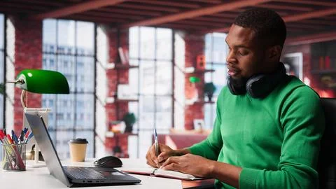 Smiling black man taking notes while watching a tutorial presentation Foto stock