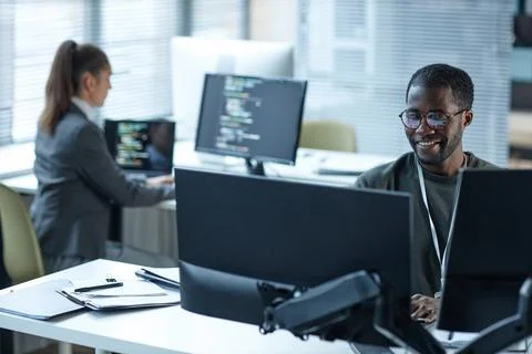 Smiling Black Man Using Computers at Workplace in Office Foto stock