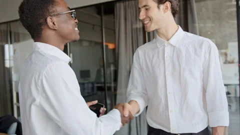 Smiling Black manager warmly greets a new White male employee and an Indian 스톡 동영상 335762506