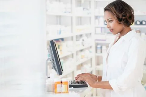 Smiling Black pharmacist using computer Stock Photos