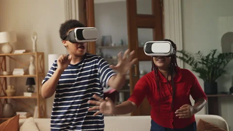 Smiling Black siblings wearing VR headsets while playing interactive video game Stock Footage 334946498