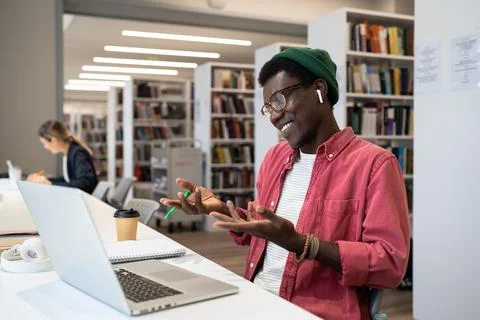 Smiling black student or freelancer in headphones using laptop looking at screen Photos