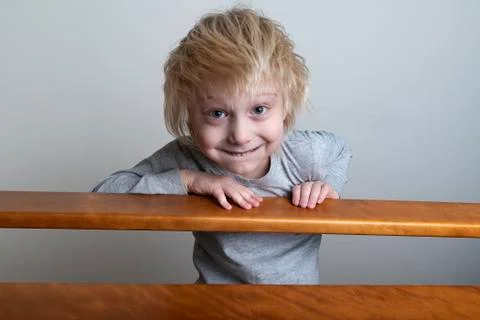 Smiling blond boy with leaned over the banister and looks down. Playing with  Stockfoto's