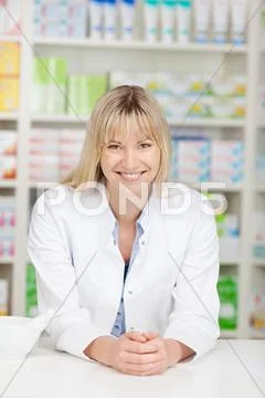 Smiling blond pharmacist leaning on counter Stock Photos