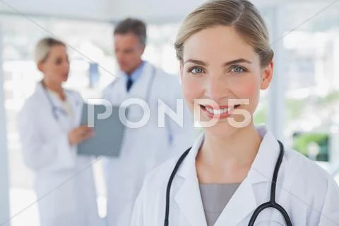 Smiling blonde haired doctor standing in her office Stock-Fotos