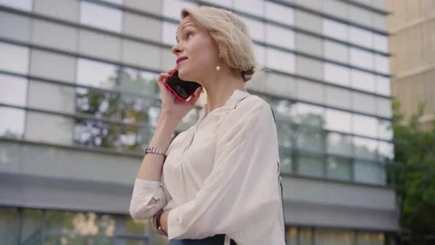 Smiling blonde middle-aged Caucasian business woman talking on cell phone Stock Footage 233471709