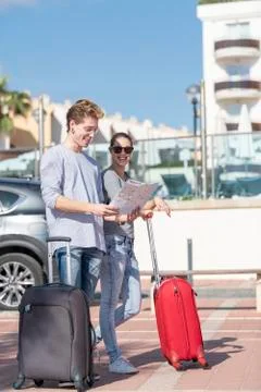 Smiling blondes looking at the map which holds the boy with expression of doubt Stock Photos
