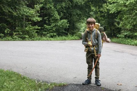 Smiling boy with backpack hiking in forest, holding apple Stock Photos