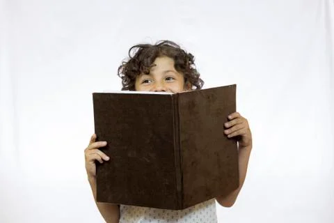 Smiling boy between 8 and 9 years old holding a book while reading Stock Photos