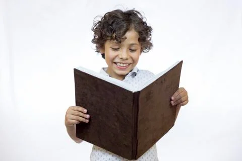 Smiling boy between 8 and 9 years old holding a book while reading Stock Photos