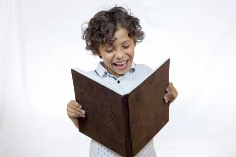 Smiling boy between 8 and 9 years old holding a book while reading Stock Photos