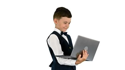 Smiling boy in a bow tie and waistcoat using laptop computer whi Stock Photos