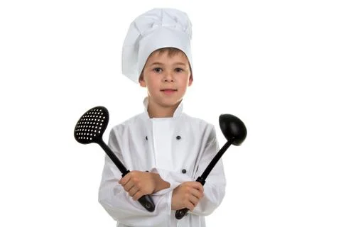 Smiling boy in chef uniform holding kitchen equipment, on white background. Stock Photos