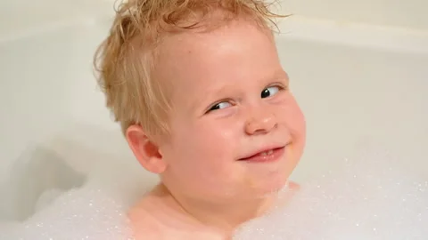 Smiling Boy Covered in Bubbles Shaking Head in Bathtub Stock Footage 307308194