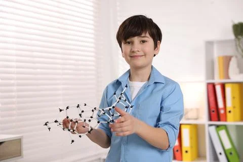 Smiling boy with DNA structure model indoors. Space for text Stock Photos