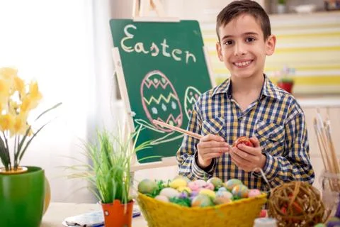 Smiling boy draws easter eggs Stock Photos